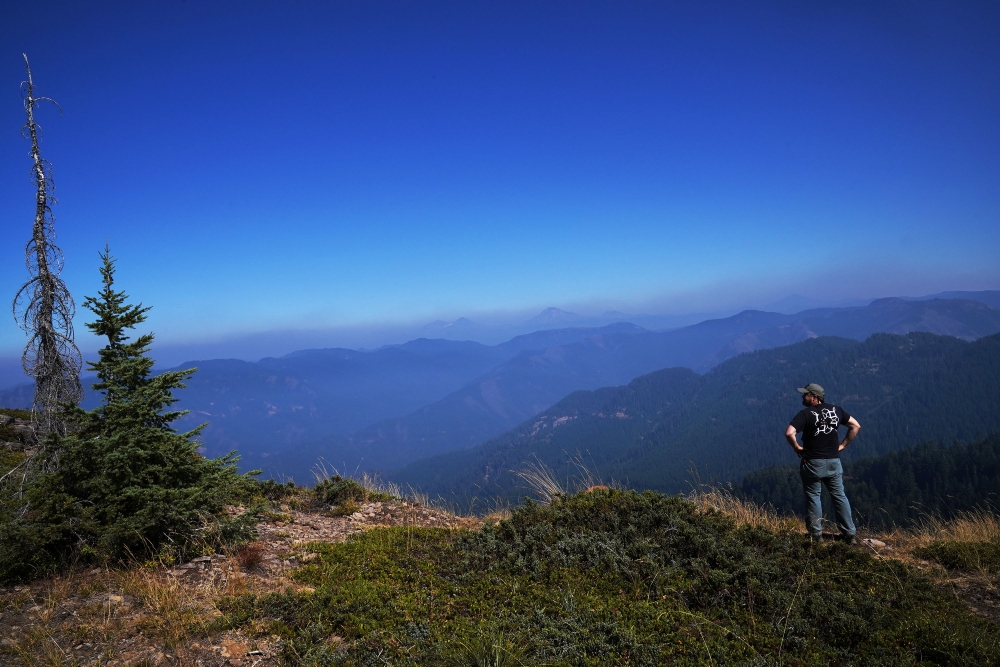Man looks over a mountain range in Oregon wearing a Momenta tshirt. 