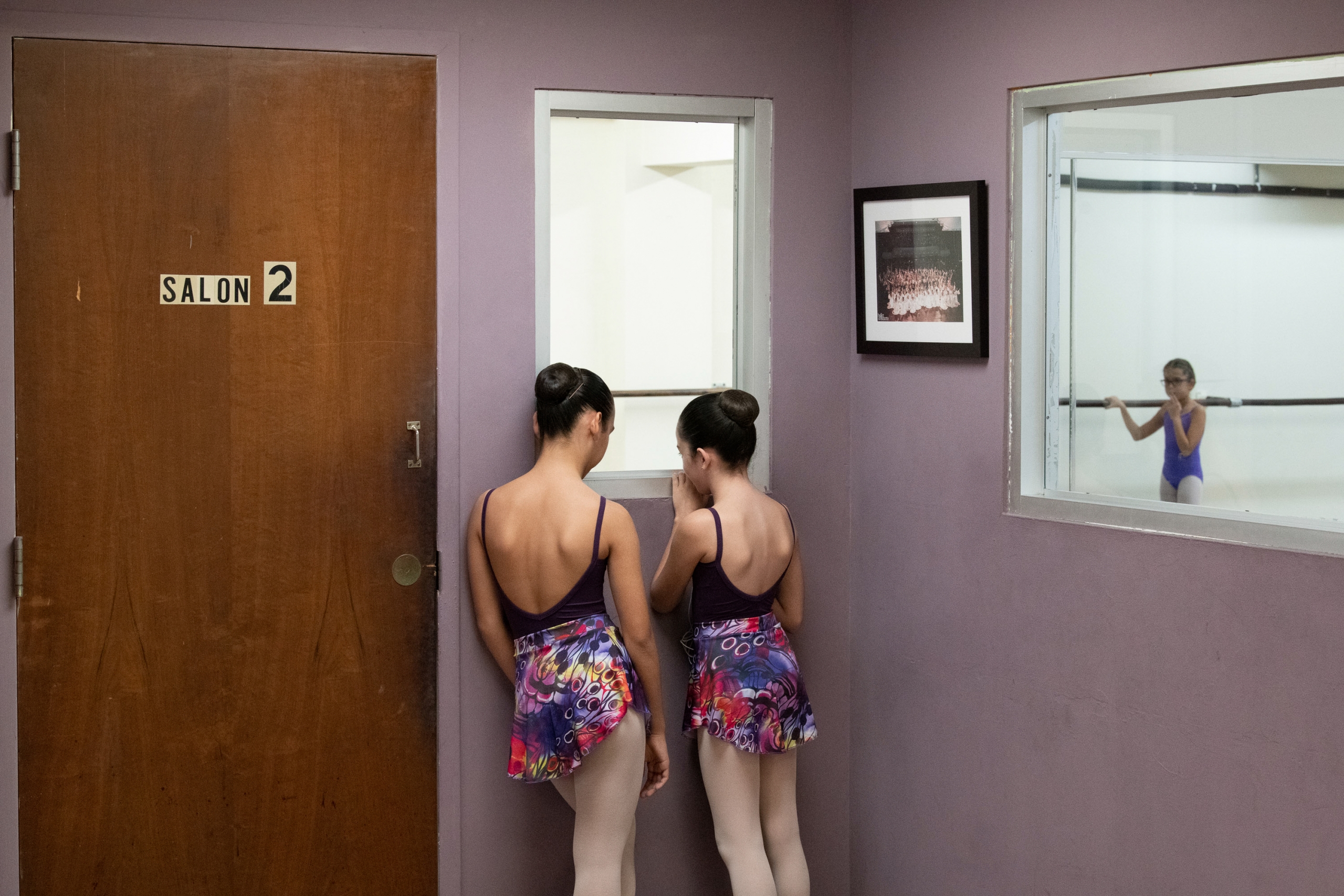 Two young dancers look into a window at a dance studio.