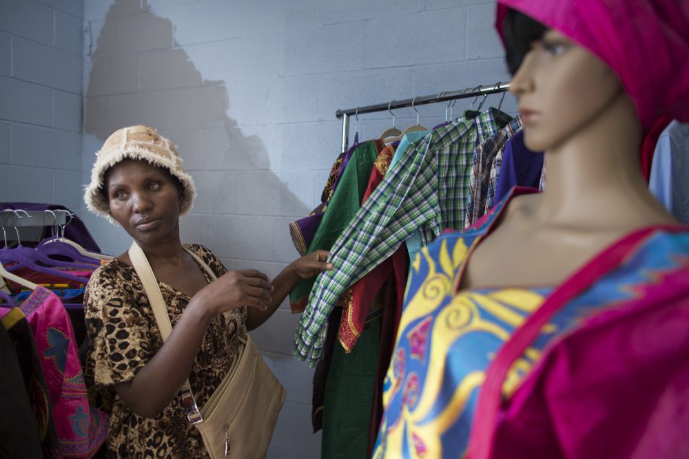 Nyirazana looks at clothes at All Nation Yesu Ni Jibu, an African clothing store in Rochester, NY. The family was unable to afford to buy new clothes, so they depended on donated clothes from a local charity and later purchased a sewing machine to make their own.