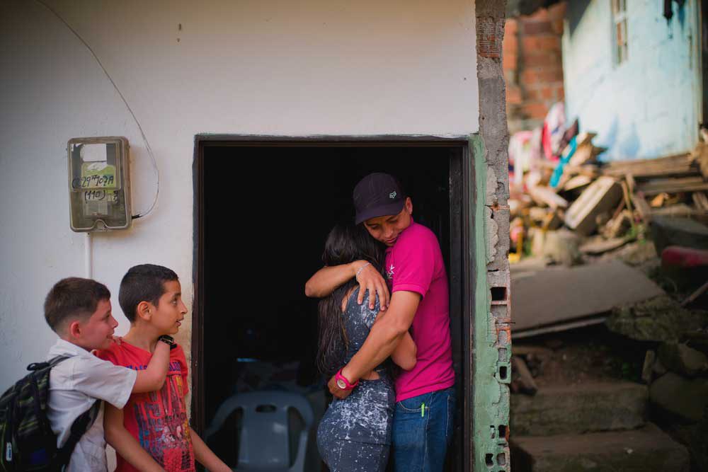 a couple hugs in the doorway in Colombia while two young childen watch